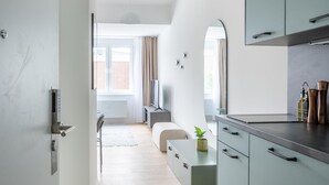 A modern kitchen with light-colored cabinets, a wooden floor, and a view to the living area. - Limehome Salzgitter A.-Schweitzer-Str. (Salzgitter)