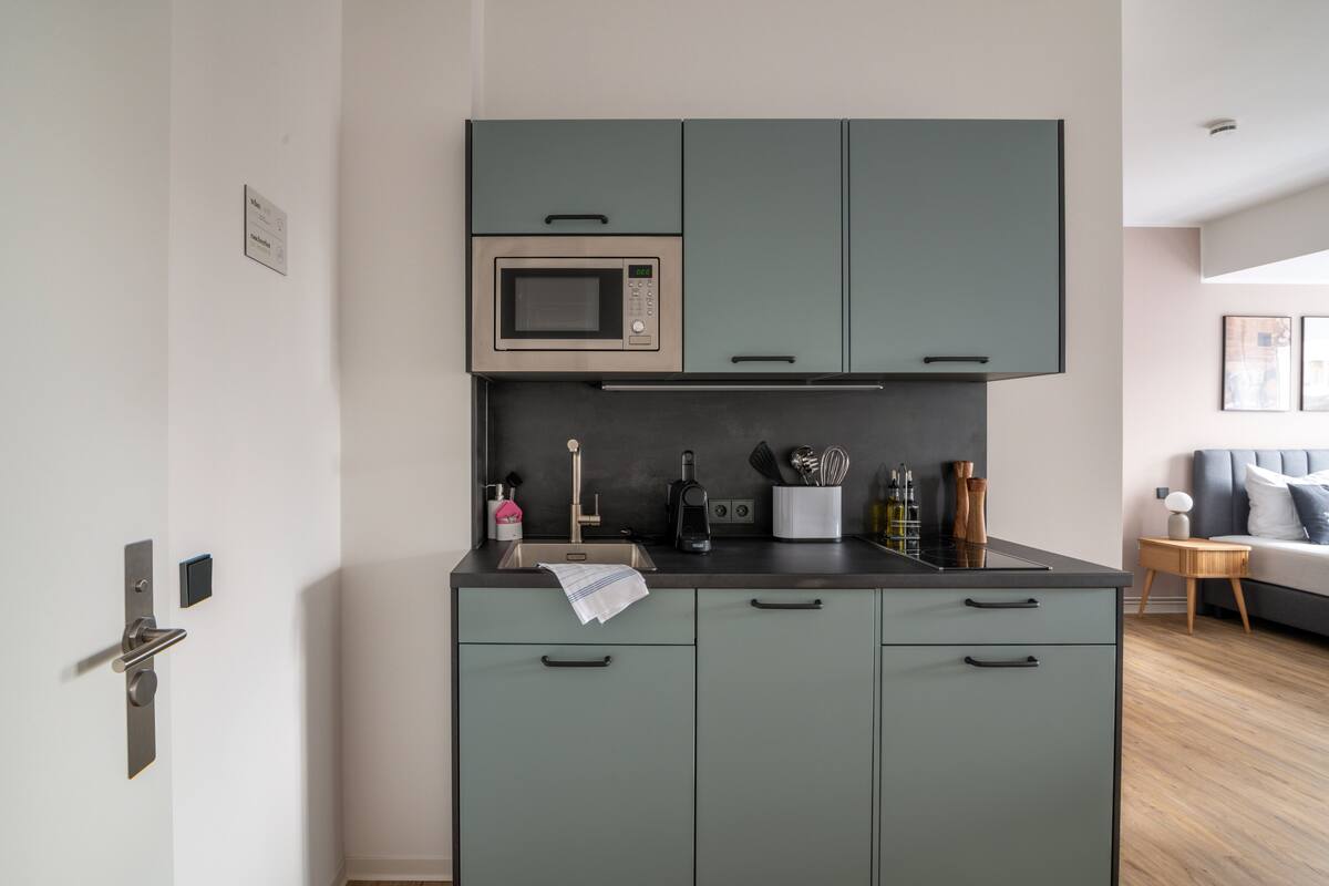 A compact kitchen with a microwave, sink, and cabinets.