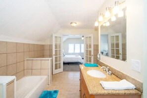 Een badkamer met een bad, een wastafel, een spiegel en een handdoek.