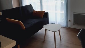 Uma sala de estar moderna com um sofá escuro, uma mesinha branca e um ventilador de teto.