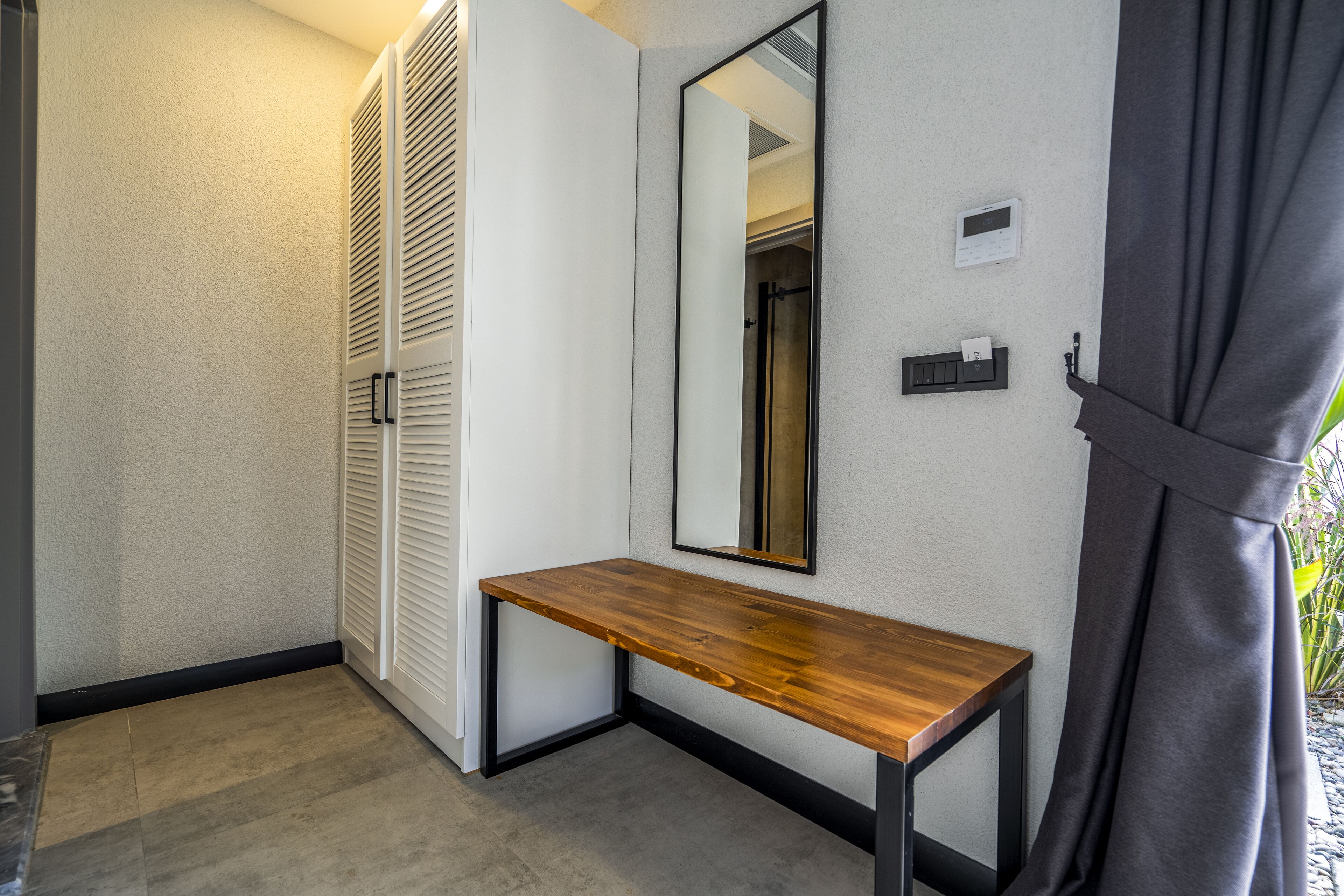 Un baño moderno con tocador de madera, un espejo grande y un perchero para toallas.