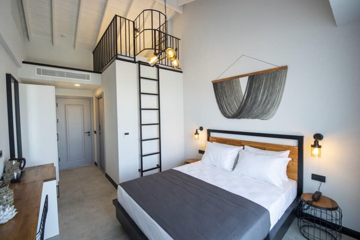 Un dormitorio con cama, escalera, lámpara colgante e iluminación en la pared.