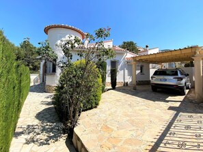 A white building with a stone pathway leading to a car parked under a pergola. - T-0521, Iwona, beautiful sunny Villa in Monte Solana (Pedreguer)