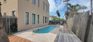Relax by the rectangular pool surrounded by a deck and a brick wall.
