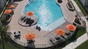 Zona de piscina con vista al océano, rodeada de sillas de descanso y sombrillas.