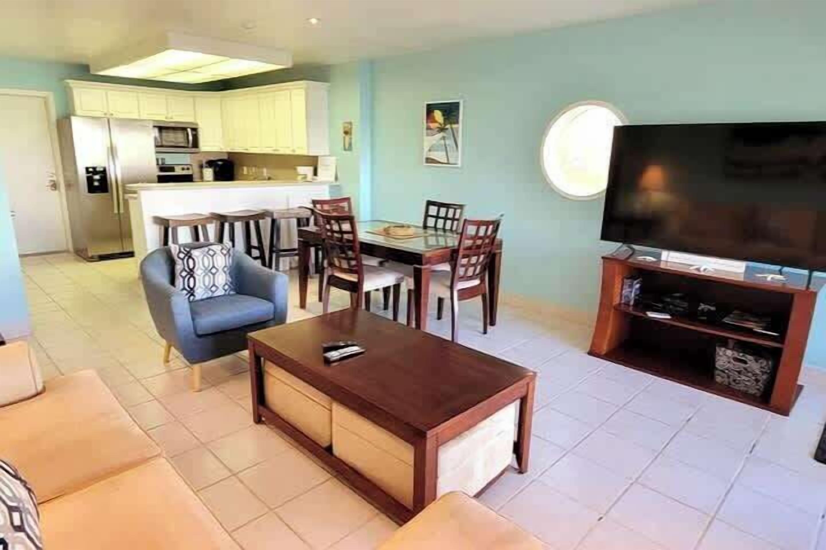 Ein Wohnzimmer mit einer Couch, einem Couchtisch, einem Fernseher und einem Essbereich mit Stühlen und einem Tisch.