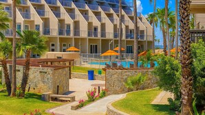 Un hotel con varios balcones, piscina y palmeras.