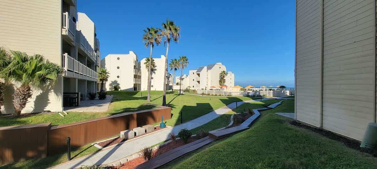 A modern hotel with a landscaped courtyard, palm trees, and a clear view of the ocean.