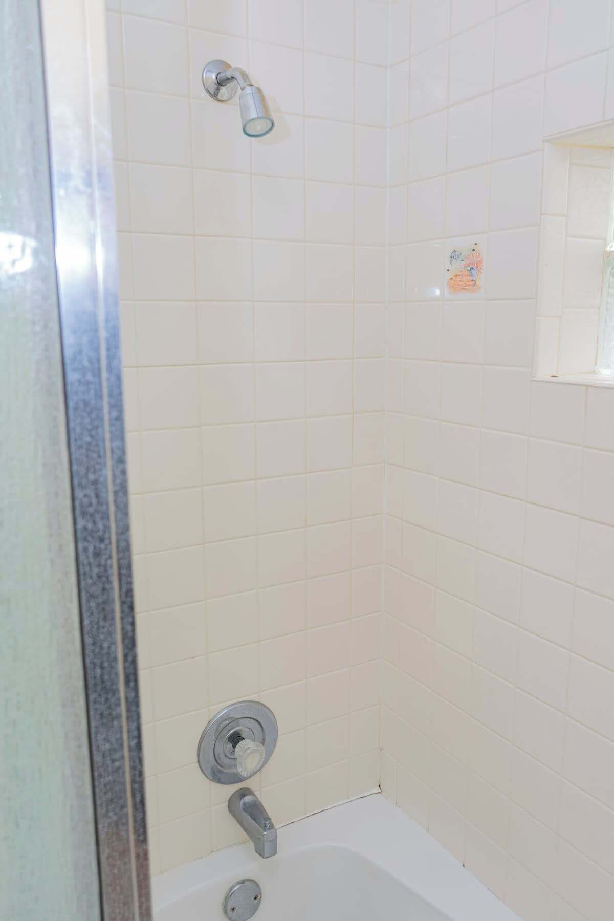 A shower with a handheld showerhead and a wall-mounted faucet.