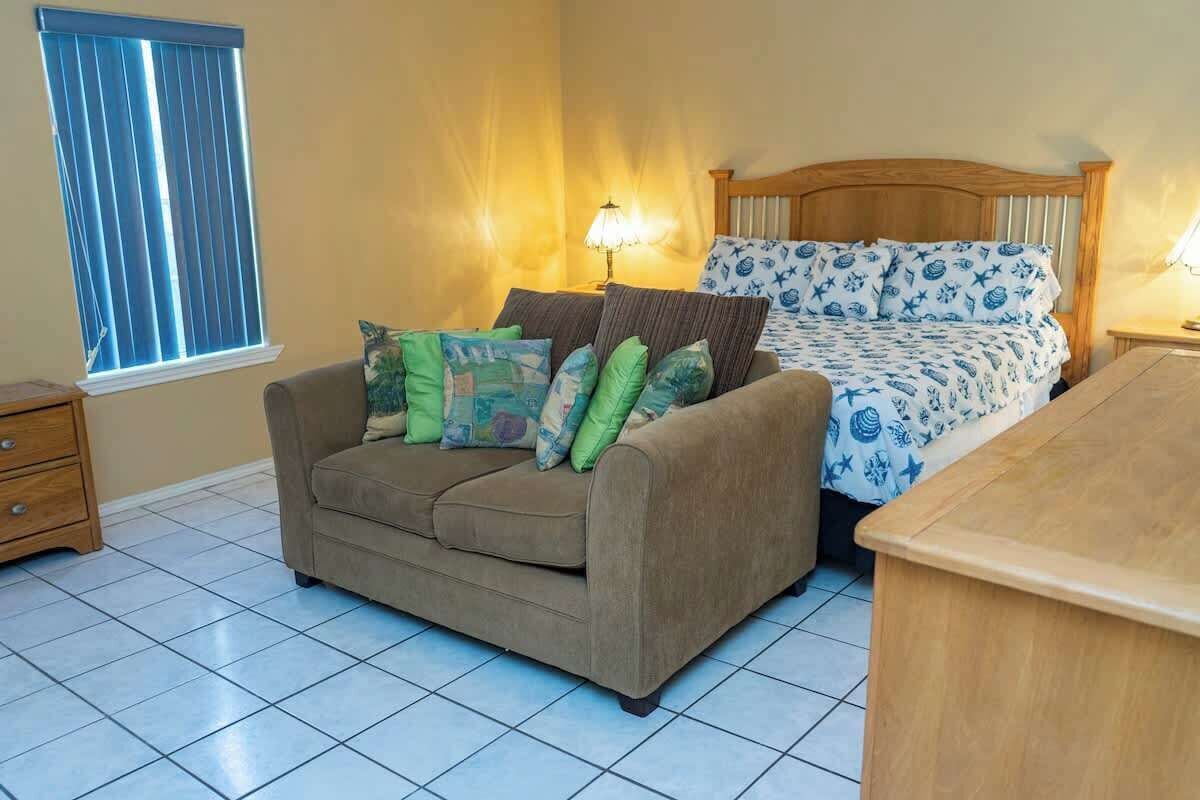 A room with a bed, a sofa, and a nightstand.