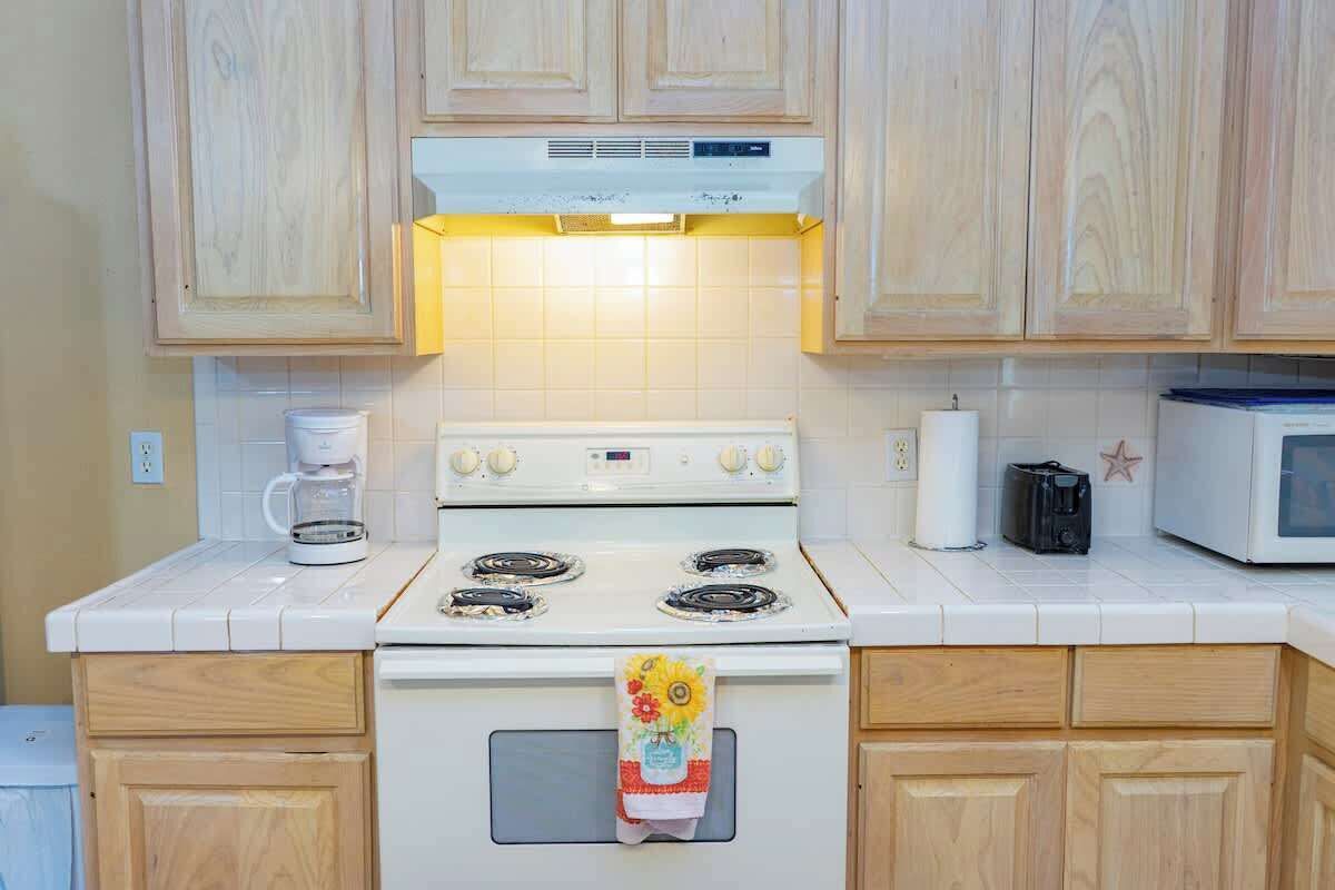 A kitchen with wooden cabinets, a white stove, a microwave, and a coffee maker.