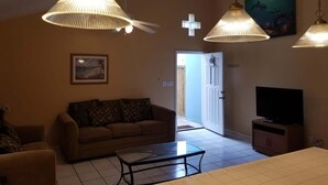 A living room with a sofa, coffee table, TV, and pendant lights.
