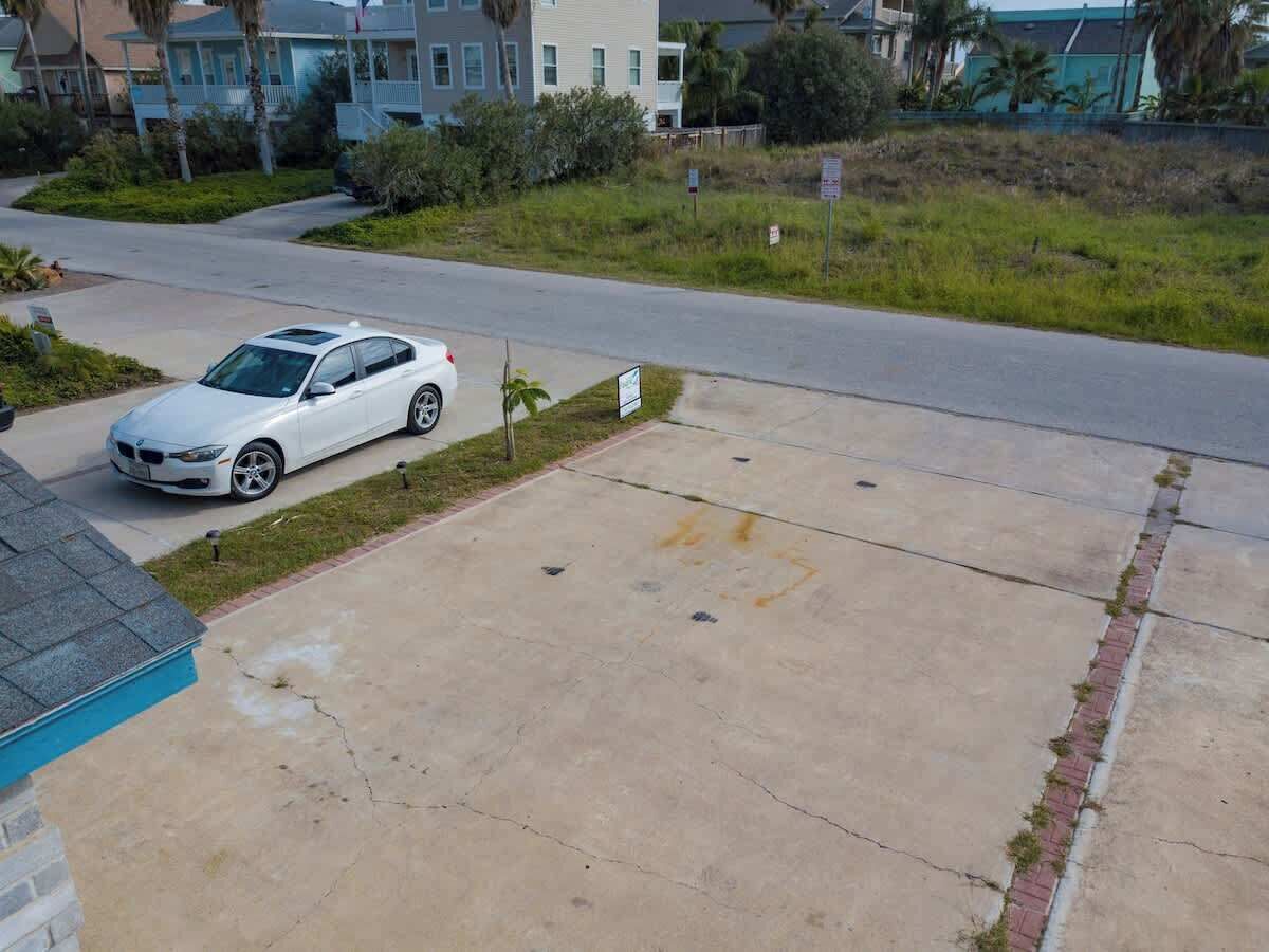 A residential driveway with a white car parked on the left.