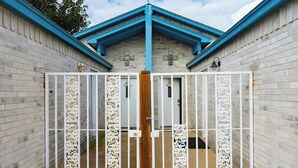A gated entrance with a decorative white metal gate and a wooden post.