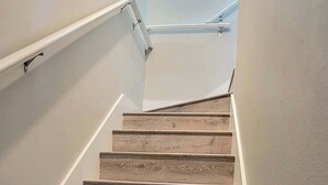 A staircase with wooden steps and white handrails, leading upwards. - Bungalow Tarvana #2 (Port Isabel)