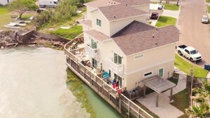 A multi-story building with balconies, a covered outdoor seating area, and a view of a river. - Bungalow Tarvana #2 (Port Isabel)