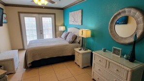 A bedroom with a bed, nightstands, a dresser, and a wall-mounted mirror.