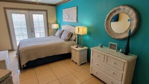 A bedroom with a bed, bedside tables, a dresser, a mirror, and a window. - Campeche Triplex Unit B (South Padre Island)