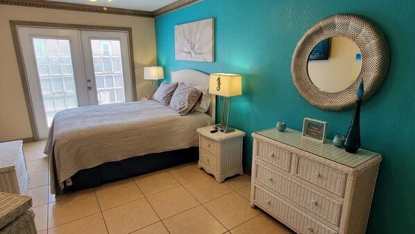 A bedroom with a bed, bedside tables, a dresser, a mirror, and a window. - Campeche Triplex Unit B (South Padre Island)