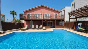 A swimming pool with lounge chairs and a covered patio area. - Campeche Triplex Unit B (South Padre Island)
