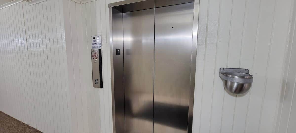 A metallic elevator with a number plate indicating it is the fourth floor.