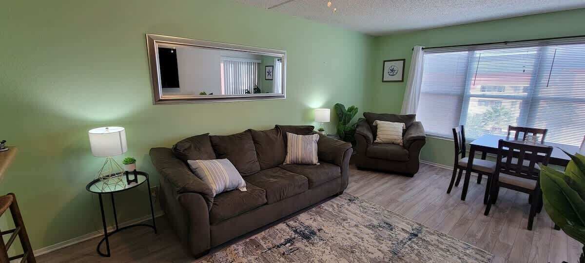 A living room with two couches, a dining table, chairs, a lamp, and a mirror on the wall.