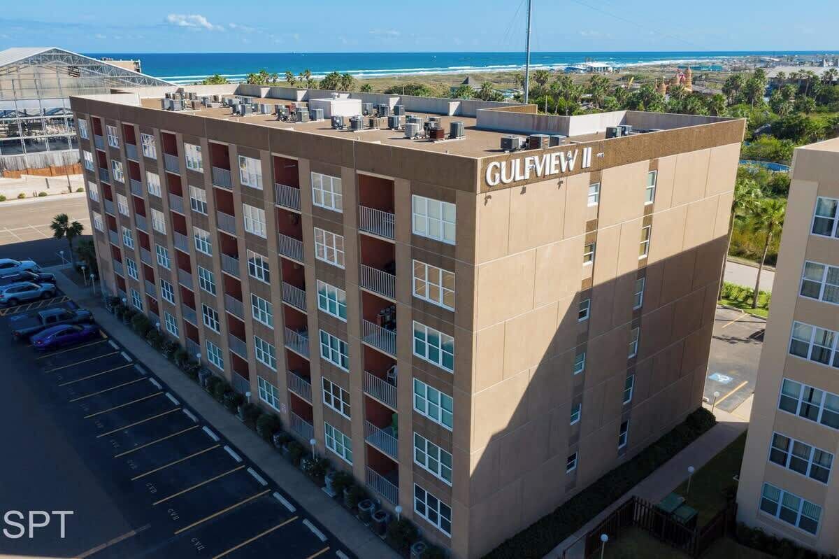 Un immeuble à plusieurs étages, nommé « GULFVILLE », avec un parking situé devant.