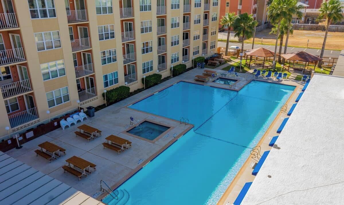 Een hotel met een groot zwembad, terras en uitzicht op de omgeving.