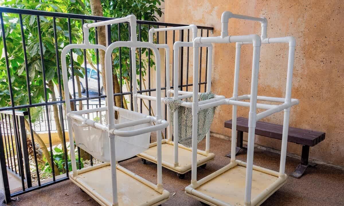 A balcony with a metal railing, a white metal shelf unit, and a bench.