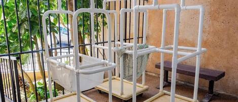 A balcony with a metal railing, a white metal shelf unit, and a bench.