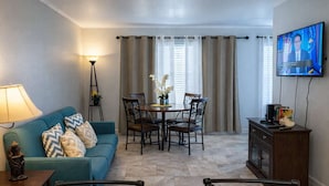Een woonkamer met een bank, eettafel, stoelen, een televisie en een lamp.