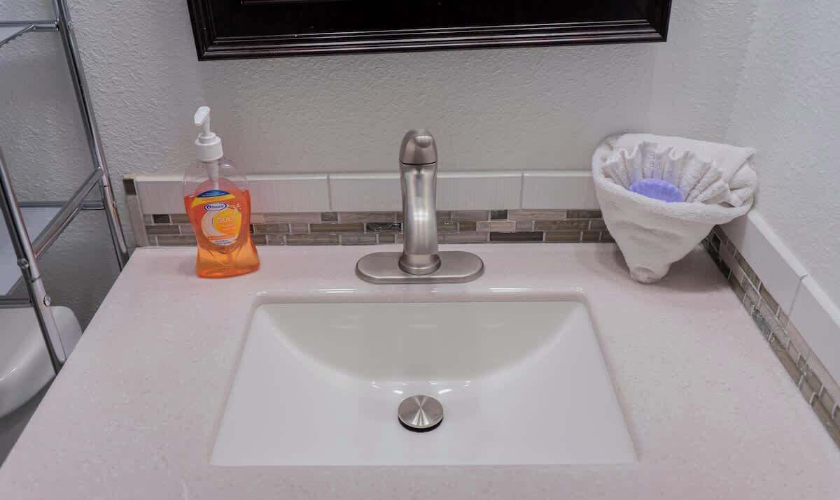 Un lavabo de salle de bain doté d’un robinet moderne, d’un distributeur de savon et d’un porte-serviettes.