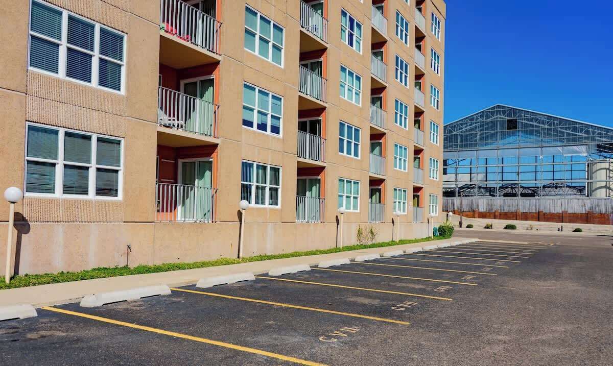 A multi-story parking lot adjacent to a building with balconies and large windows.