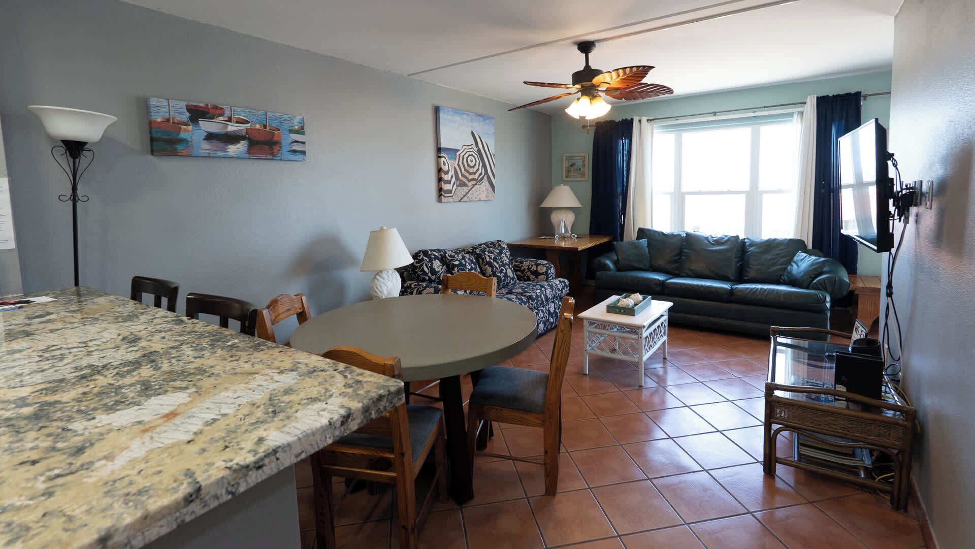 A living room with a dining area, a ceiling fan, and artwork on the walls.