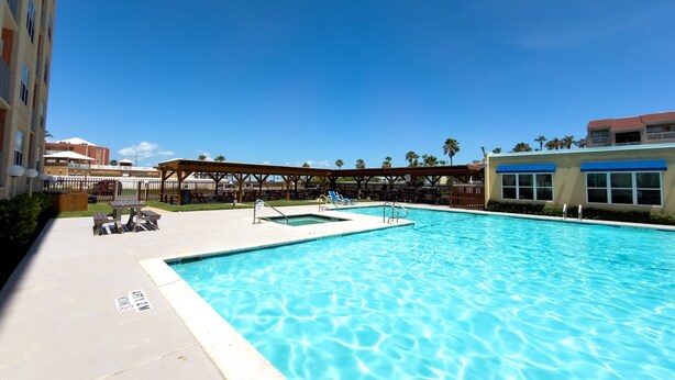 A swimming pool with lounge chairs and a covered seating area.