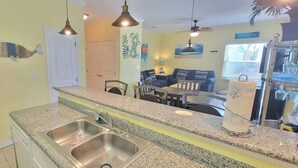 A kitchen with granite countertops, stainless steel sinks, and pendant lighting.