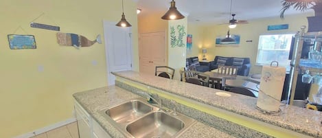 A kitchen with granite countertops, stainless steel sinks, and pendant lighting.