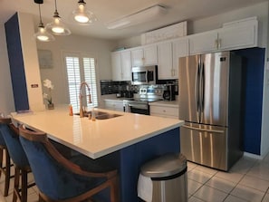 Enjoy cooking in this well-equipped kitchen with a central island, stainless steel appliances, and ample counter space.