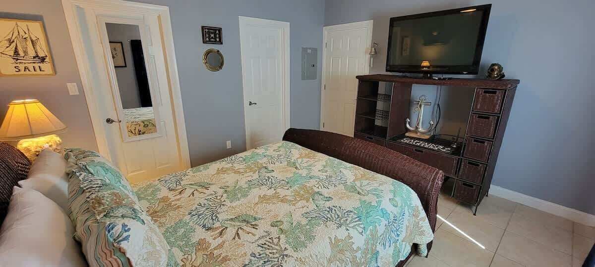 A bedroom with a bed, a dresser, a television, and a door.