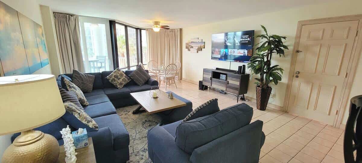 Una sala de estar con un sofá, una mesa de centro, un televisor y una planta.