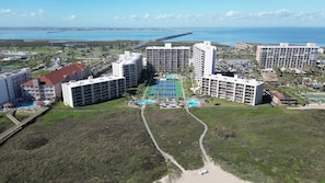 Un hotel di grandi dimensioni con numerosi piani, un cortile centrale con campo da tennis e vista sull'oceano.
