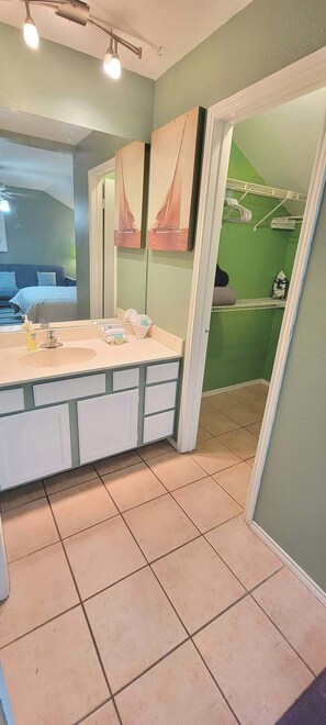 A bathroom with a large vanity, a mirror, and a green wall. - Sparky's Pool House (South Padre Island)