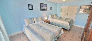 A room with two beds, a nightstand, and a wardrobe. - Sparky's Pool House (South Padre Island)