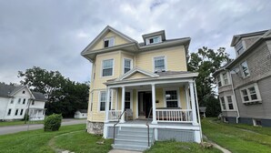 Ein zweistöckiges Haus mit Veranda und kleinem Vorgarten.