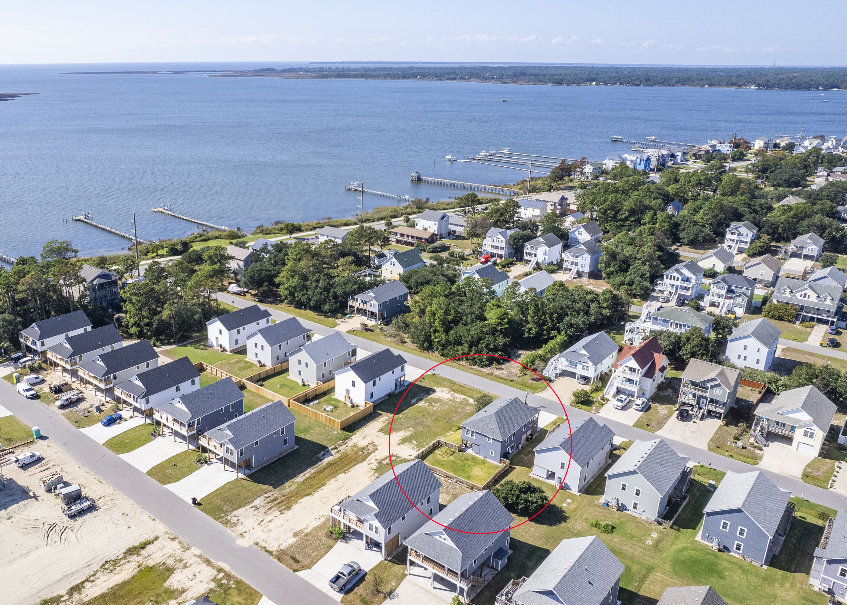 An aerial view of a residential area with houses, a dock, and a body of water.