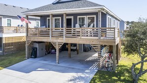 Ein zweistöckiges Haus mit überdachter Veranda, Garage und einem draußen abgestellten Fahrrad.
