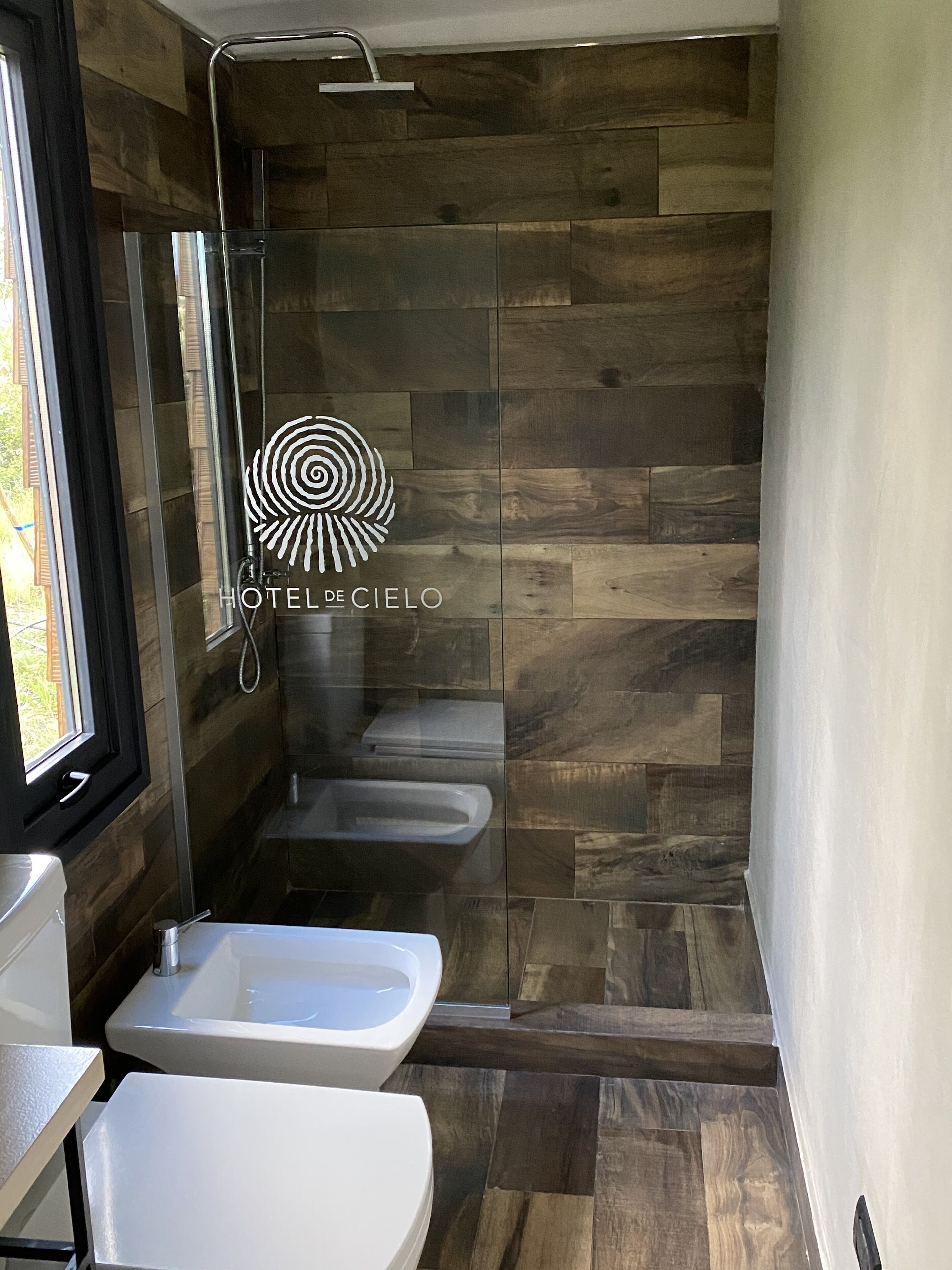 Un baño moderno con ducha, dos lavamanos y un inodoro.