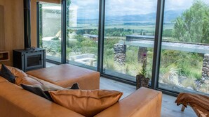 Un salon moderne doté d’une grande fenêtre offrant une vue panoramique sur un paysage montagneux.