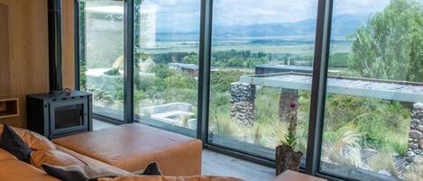 Un salón moderno con un ventanal grande que ofrece una vista panorámica de un paisaje montañoso.