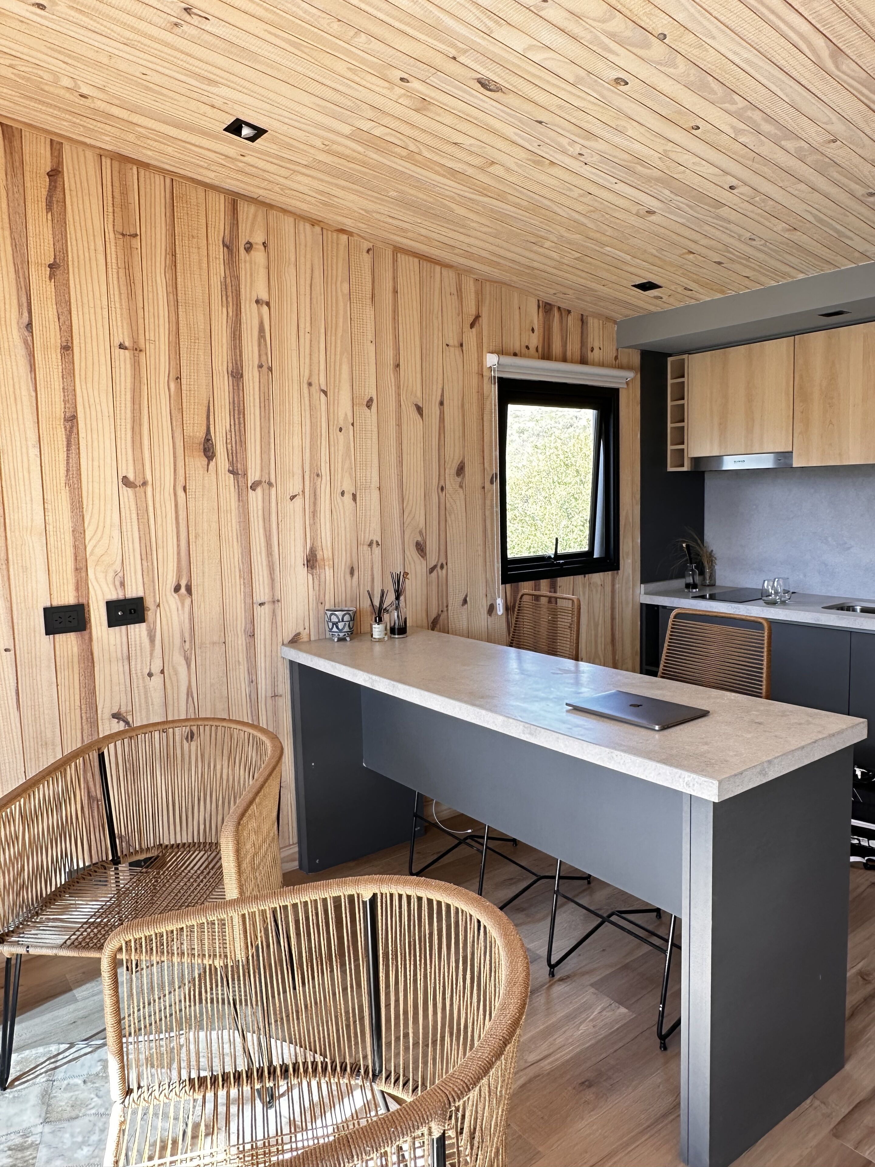Une cuisine moderne avec un lambris en bois, un grand îlot central et une fenêtre.